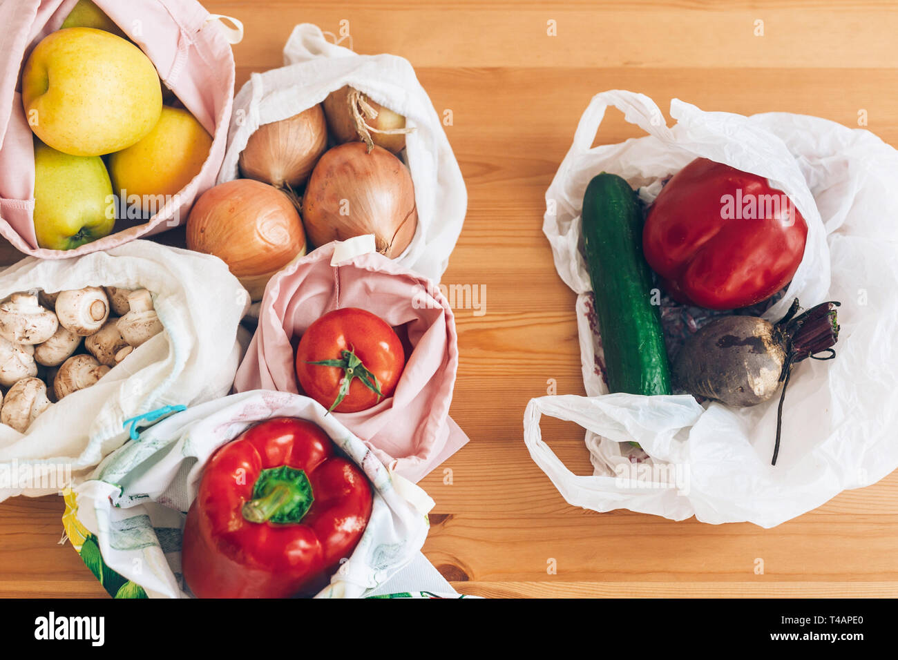 Frische Lebensmittel in wiederverwendbaren eco Taschen und Gemüse in Kunststoff Polyethylen Beutel auf Holztisch. Verbot single use Kunststoff. Kunststoff, kostenlosen Elemente wählen. Re Stockfoto