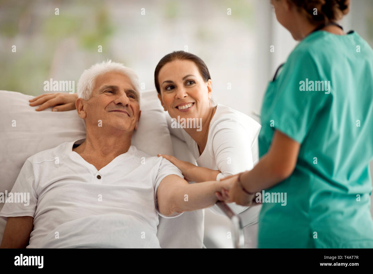 Älterer Mann im Krankenhaus Bett, erhält Besuch von seiner Frau. Stockfoto