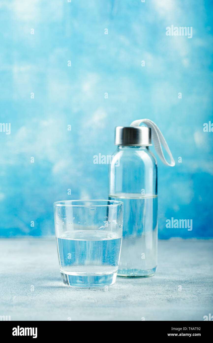 Glas Wasser mit einer Flasche am Tisch Stockfoto