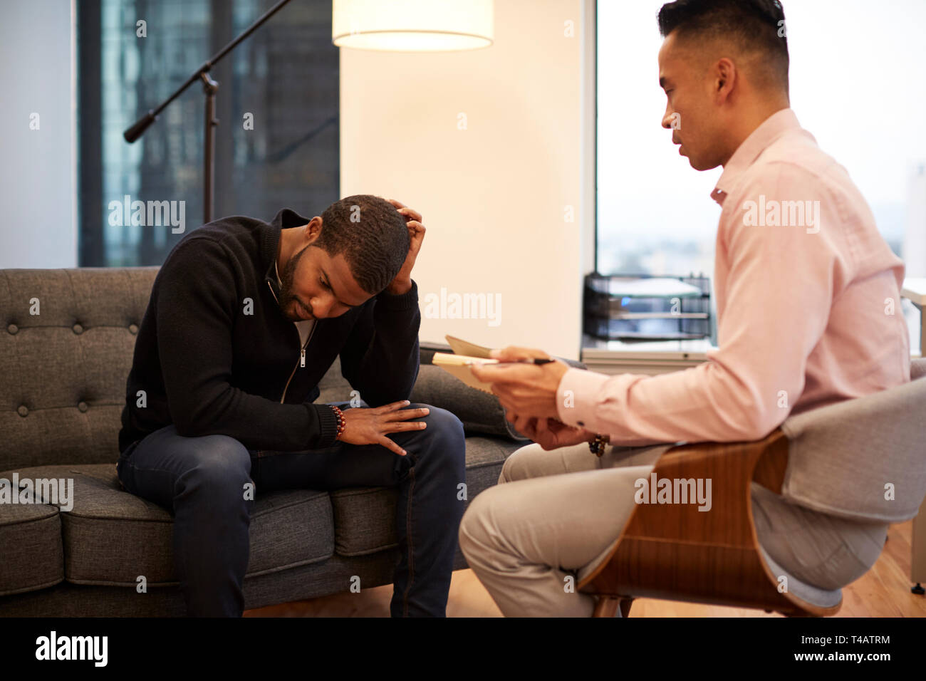 Unglückliche Mann sitzt auf der Couch treffen mit männlichen Ratgeber in Office Stockfoto