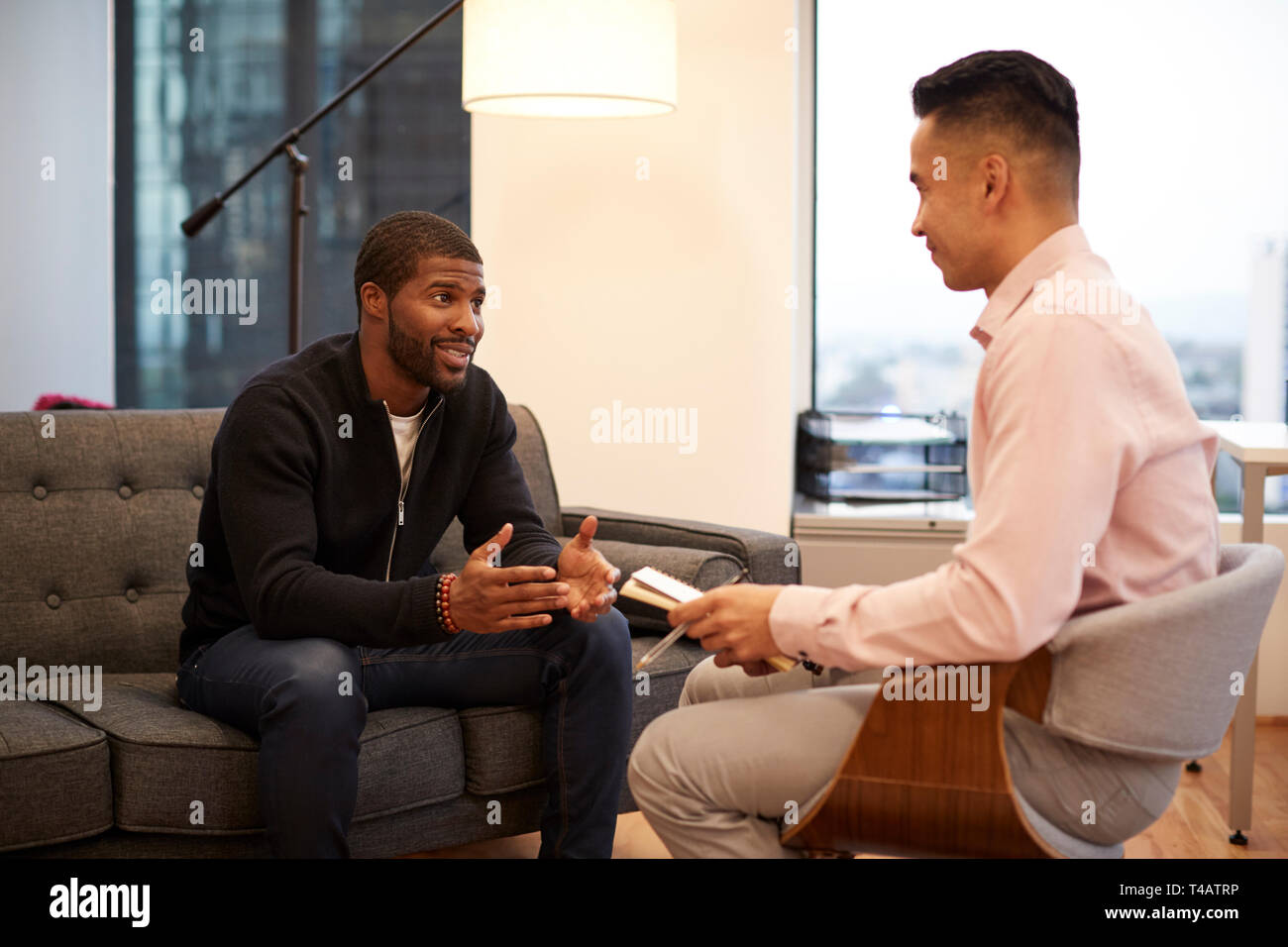 Mann sitzt auf der Couch treffen mit männlichen Ratgeber in Office Stockfoto