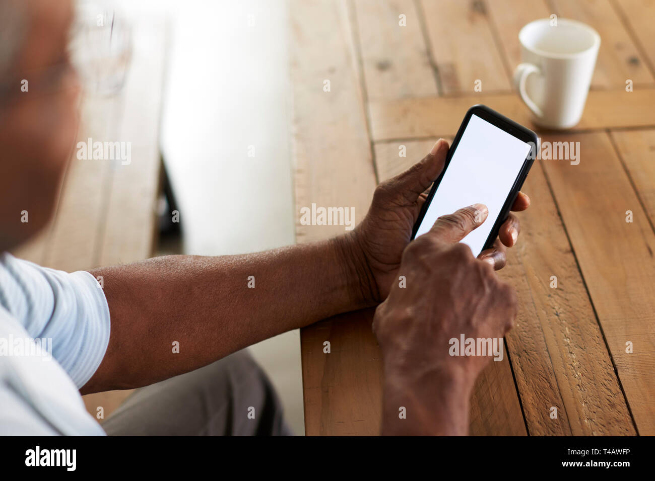 Älteren schwarzen Mann an einem Tisch mit Smartphone sitzen, Blick über die Schulter Stockfoto