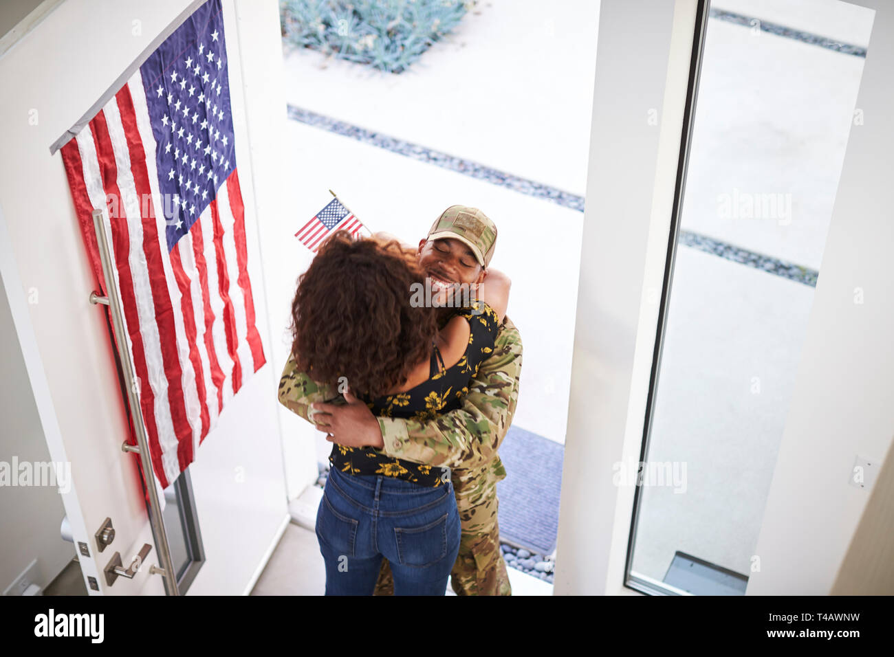 Ansicht der Rücksendung männlichen Schwarzen Soldat seine Frau umarmt in der Tür ihres Hauses Stockfoto