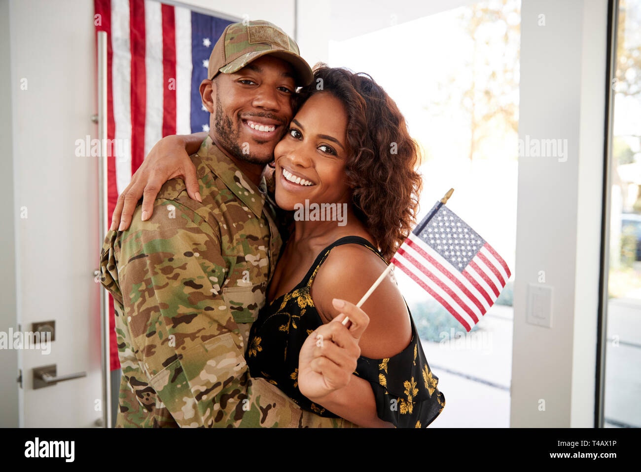 Tausendjährige schwarz Soldat und Frau zu Hause verinnerlichen und lächelnd auf Kamera, wehende Flagge, in der Nähe Stockfoto