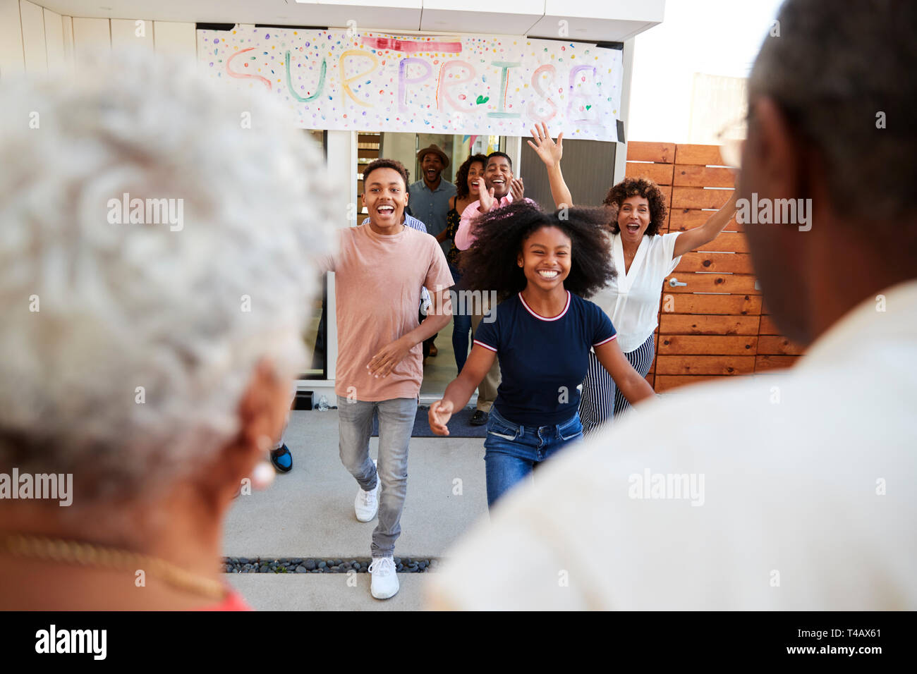 Blick über die Schulter, der Familie, den Großeltern für eine Überraschung Familie Welcome Party Stockfoto