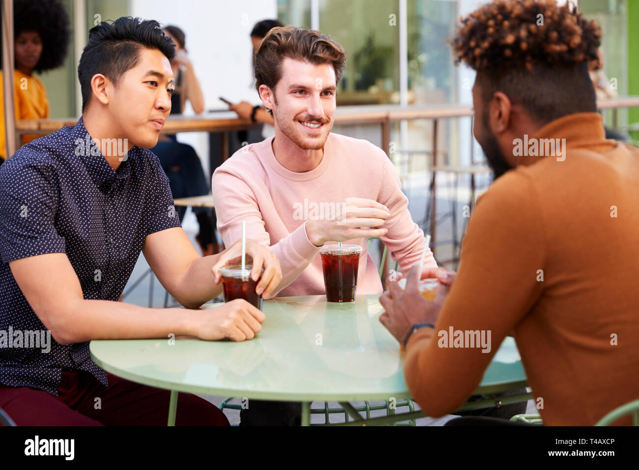 Drei tausendjährigen männliche Freunde reden über kalten Biere außerhalb ein Cafe in der Straße der Stadt, in der Nähe Stockfoto
