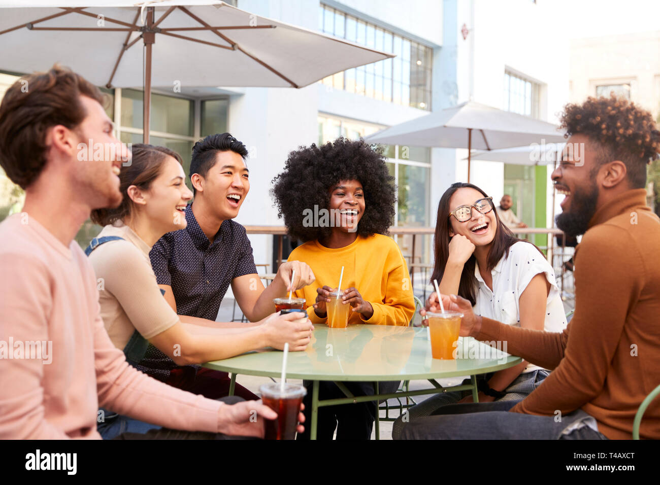 Sechs trendigen tausendjährigen Freunden trinken kalte Biere Sprechen und Lachen außerhalb eines Cafe Stockfoto
