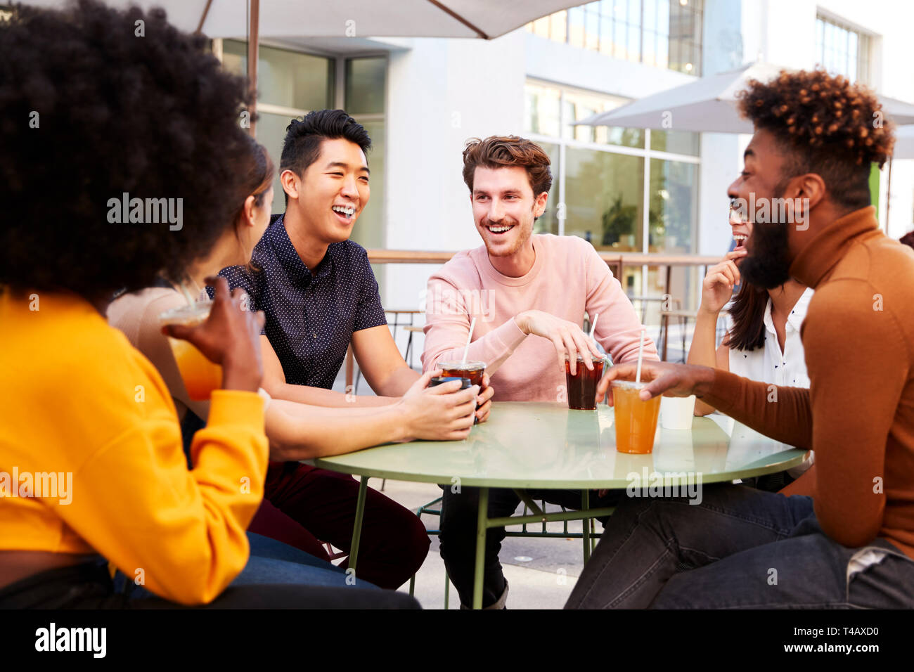 Sechs trendigen tausendjährigen Freunde trinken kalte Biere und Reden, sitzen auf der Straße vor einem Cafe Stockfoto