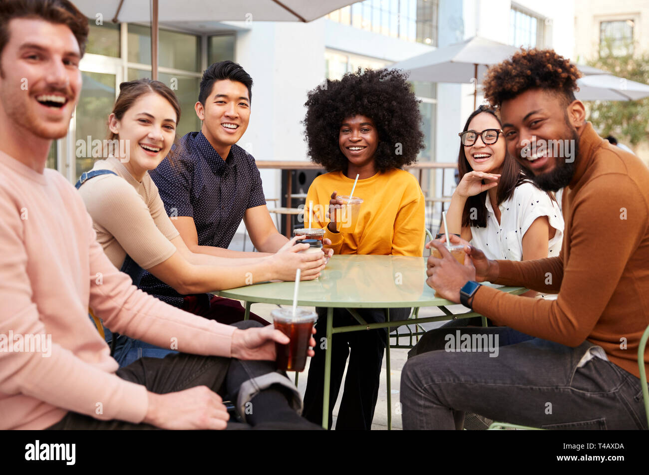 Sechs trendigen tausendjährigen Freunde sitzen Trinken außerhalb eines Cafe, drehen und lächelnd in die Kamera Stockfoto