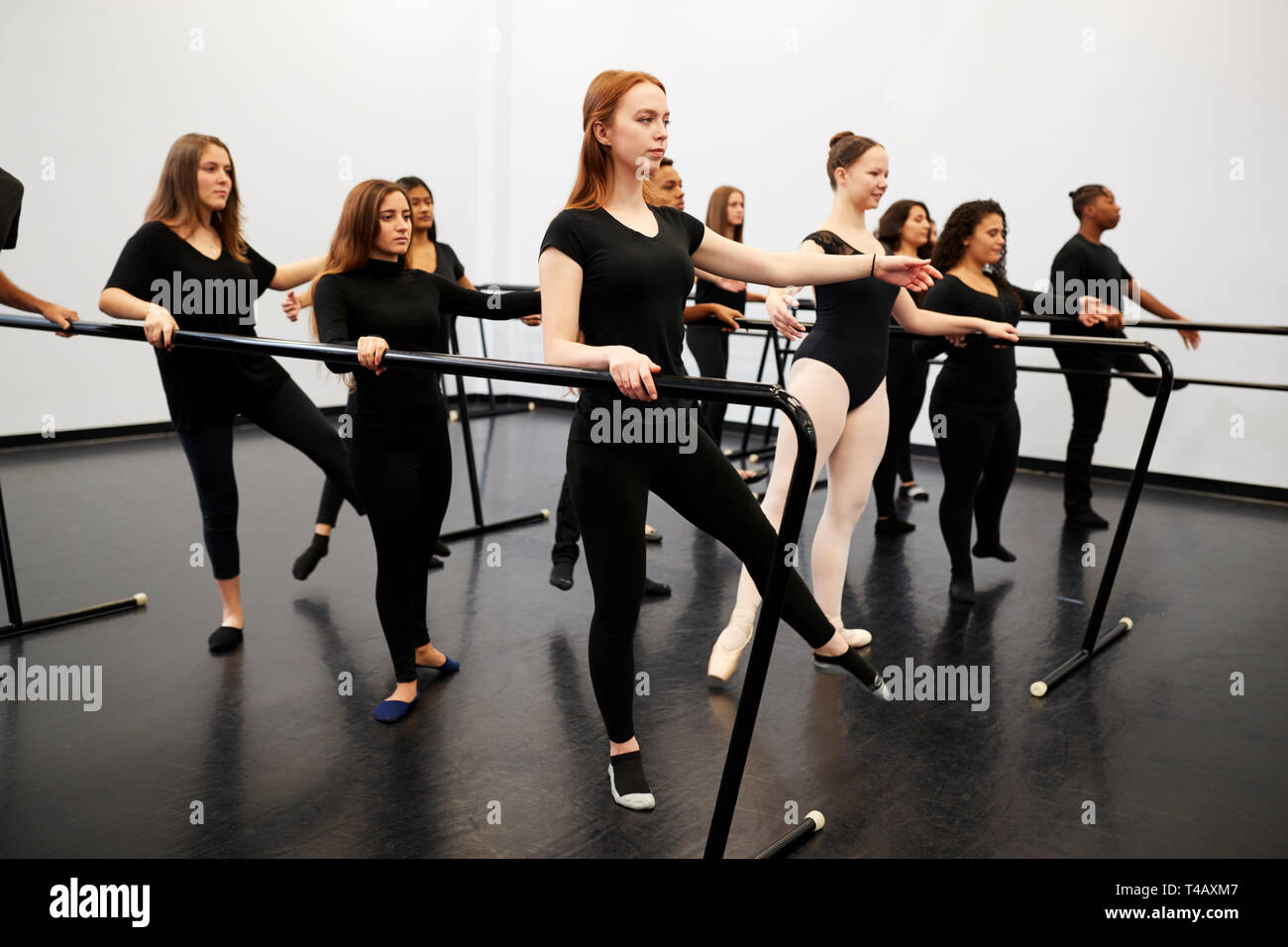 Männliche und weibliche Kursteilnehmer an der Performing Arts School Proben Ballett im Tanzstudio mit Barre Stockfoto