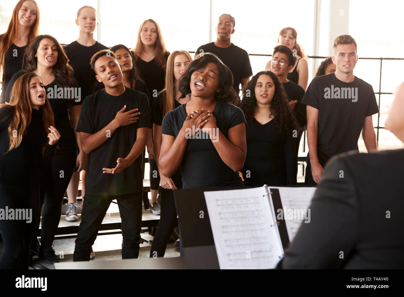 Männliche und weibliche Schüler singen im Chor mit Lehrer an der Schule für darstellende Kunst Stockfoto