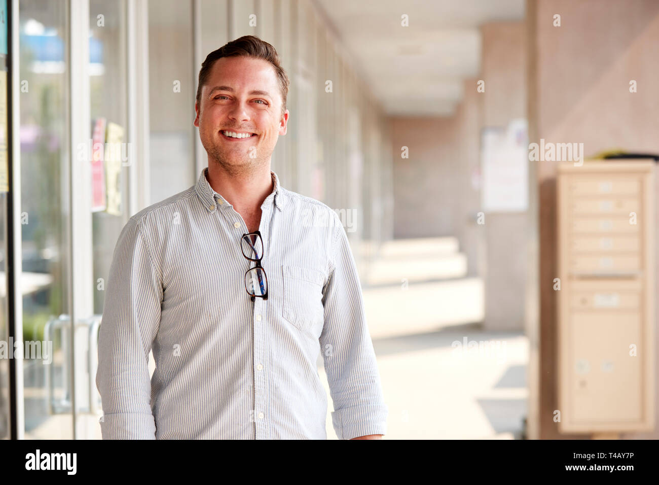 Portrait von lächelnden Männliche Lehrer stehen im Korridor der Hochschule Gebäude Stockfoto