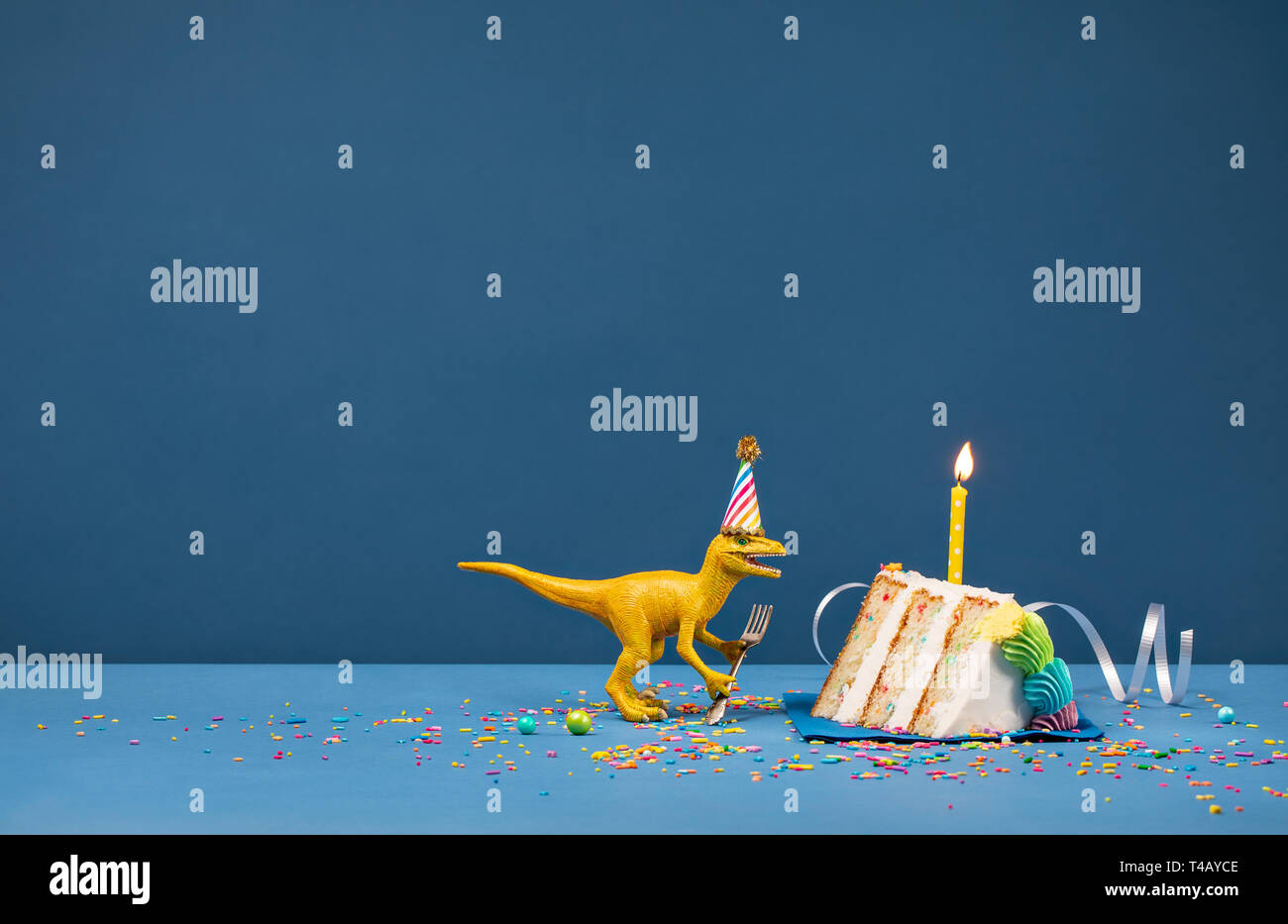 Spielzeug Dinosaurier Holding eine Gabel und Ausblasen Geburtstag Kerze auf einem blauen Hintergrund Stockfoto