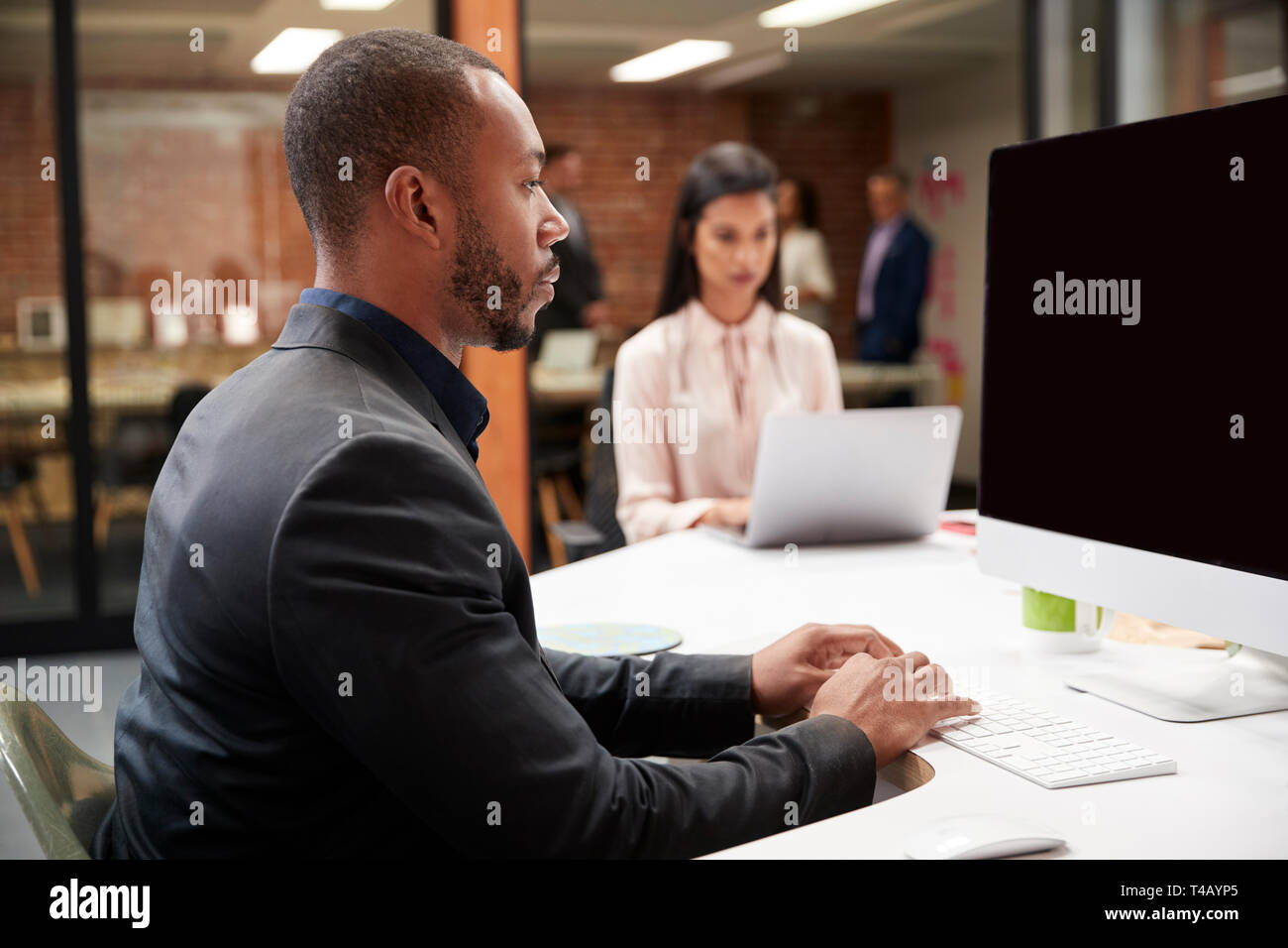 Unternehmer Arbeiten am Schreibtisch auf dem Computer im Großraumbüro mit Kollegen im Hintergrund Stockfoto