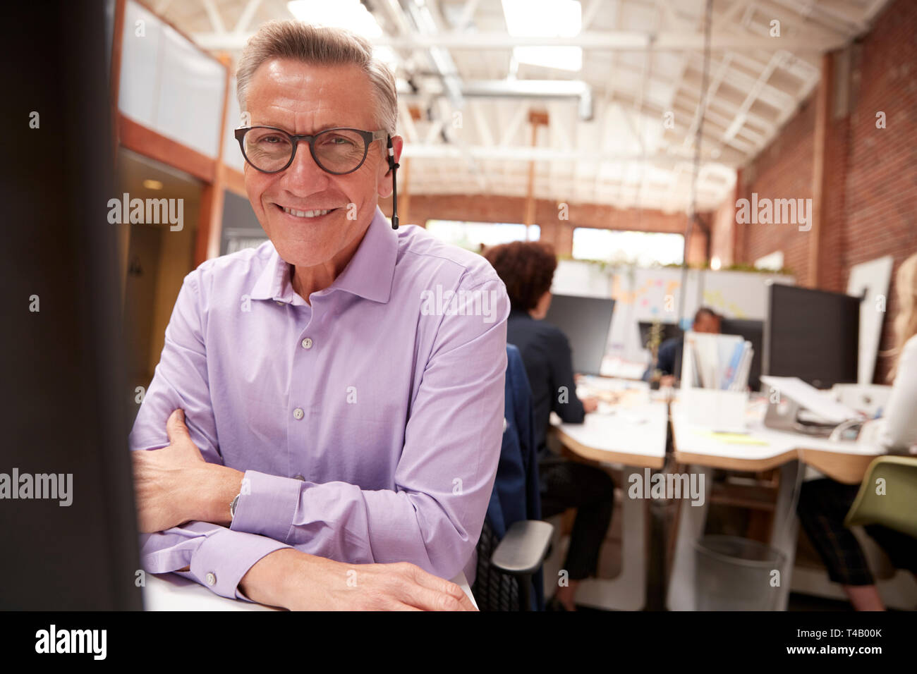 Portrait von ausgewachsenen männlichen Kunden Services Agent Arbeiten am Schreibtisch in Call Center Stockfoto