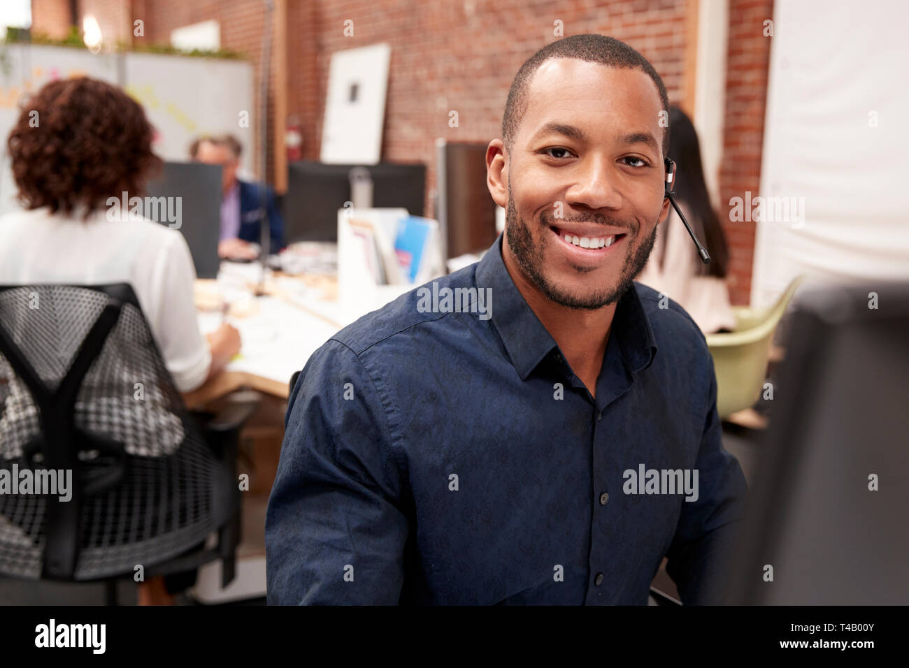 Portrait von männlichen Kunden Services Agent Arbeiten am Schreibtisch in Call Center Stockfoto