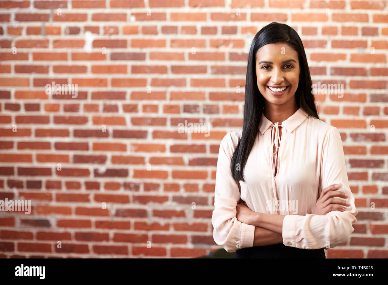 Portrait von lächelnden Jungen Geschäftsfrau Stehend gegen Mauer in modernen Büro Stockfoto
