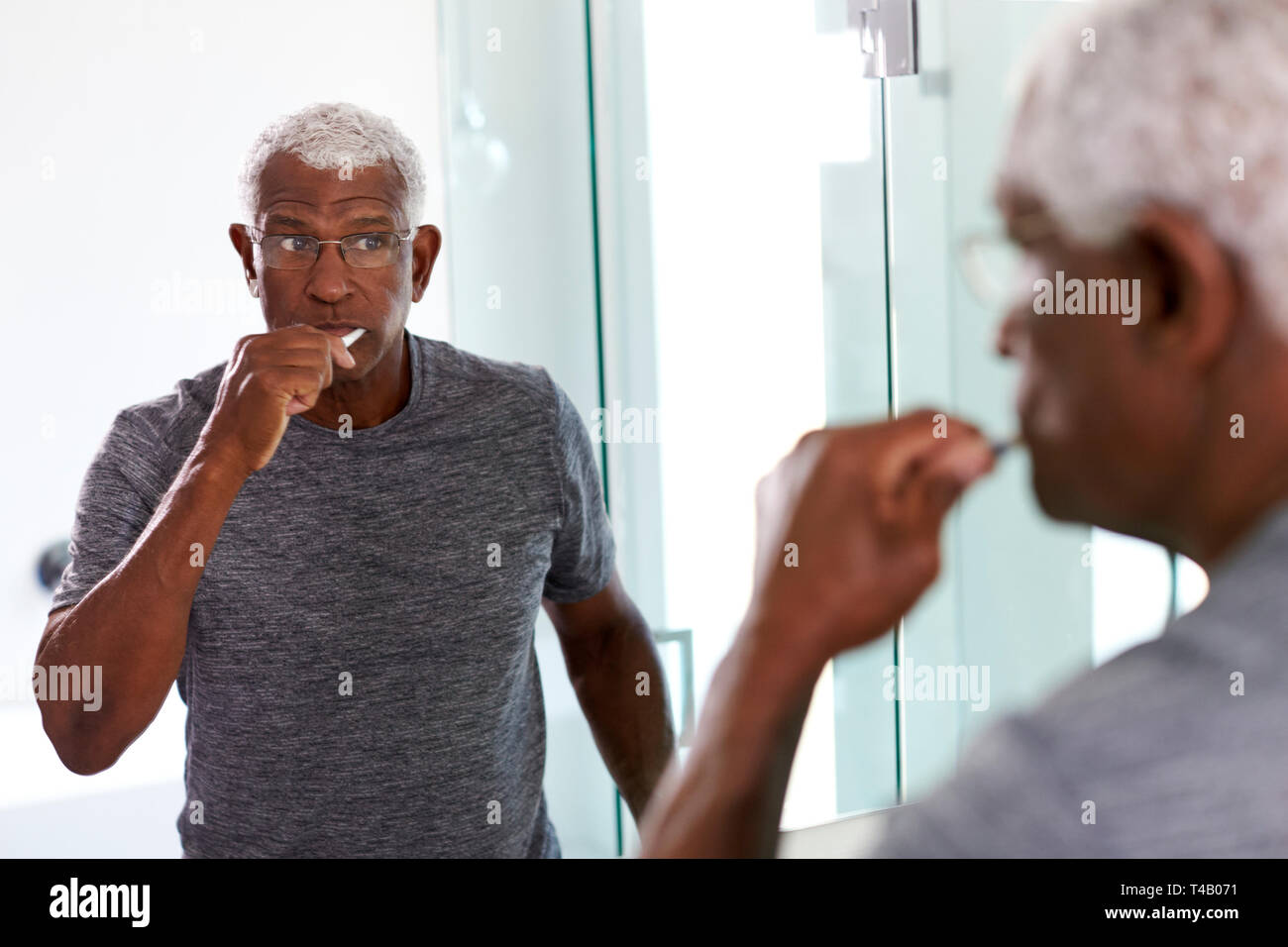 Ältere Menschen, die an der Reflexion im Badezimmer Spiegel tragen Schlafanzug Zähneputzen Stockfoto