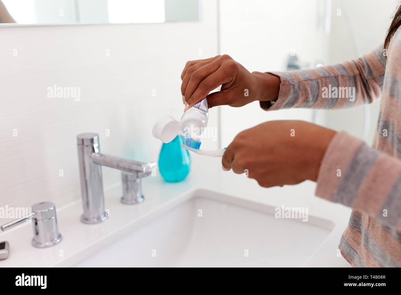 Nahaufnahme von Frau quetschen Zahnpasta auf die Zahnbürste im Badezimmer Stockfoto