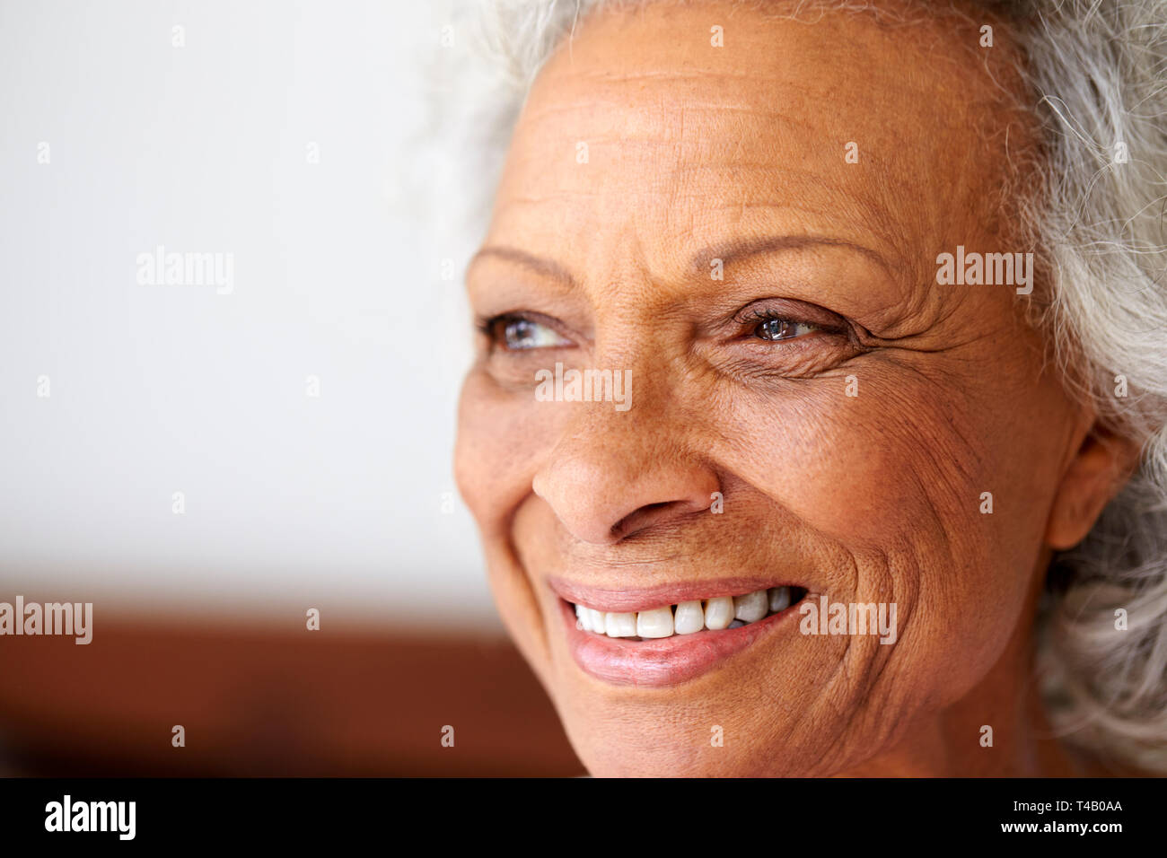 Nahaufnahme der lächelnden älteren Frau sitzt auf dem Bett zu Hause Positive Suchen Stockfoto