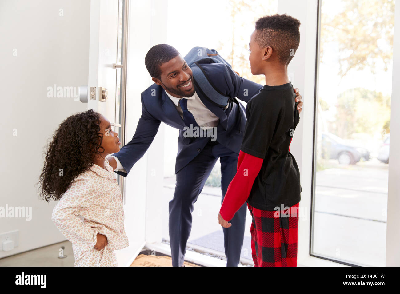 Kinder Gruß und Umarmen, Geschäftsmann, Vater, als er wieder nach Hause von der Arbeit Stockfoto