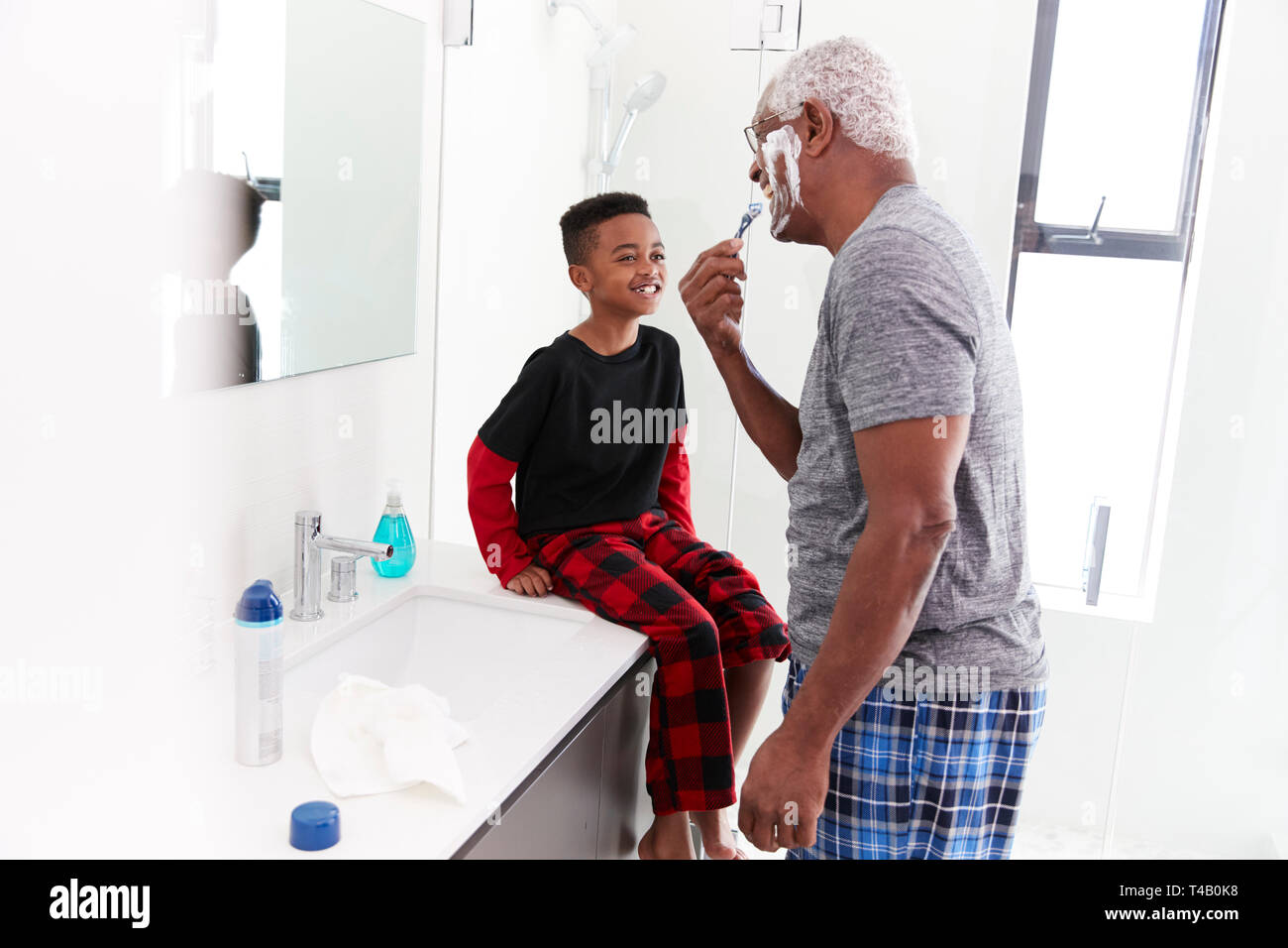 Großvater tragen Schlafanzug im Badezimmer rasieren Während Enkel Uhren Stockfoto