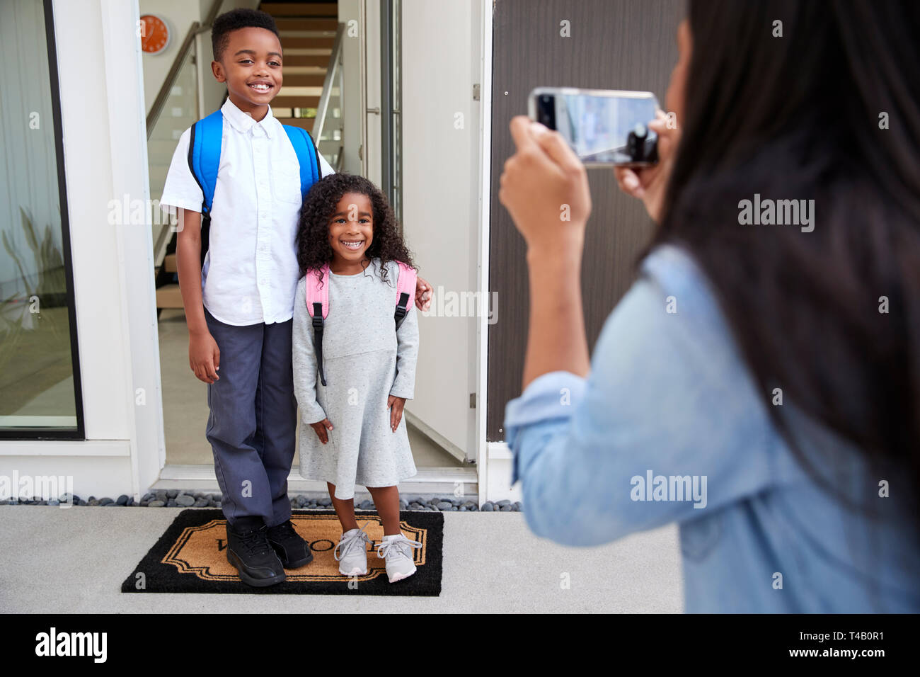 Mutter unter Foto von Kindern mit Handy am ersten Tag wieder in der Schule Stockfoto