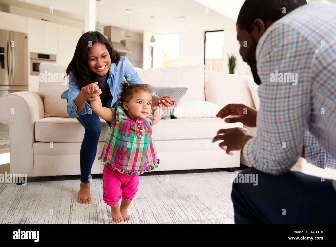 Familie zu Hause Förderung Baby Tochter Erste Schritte Stockfoto