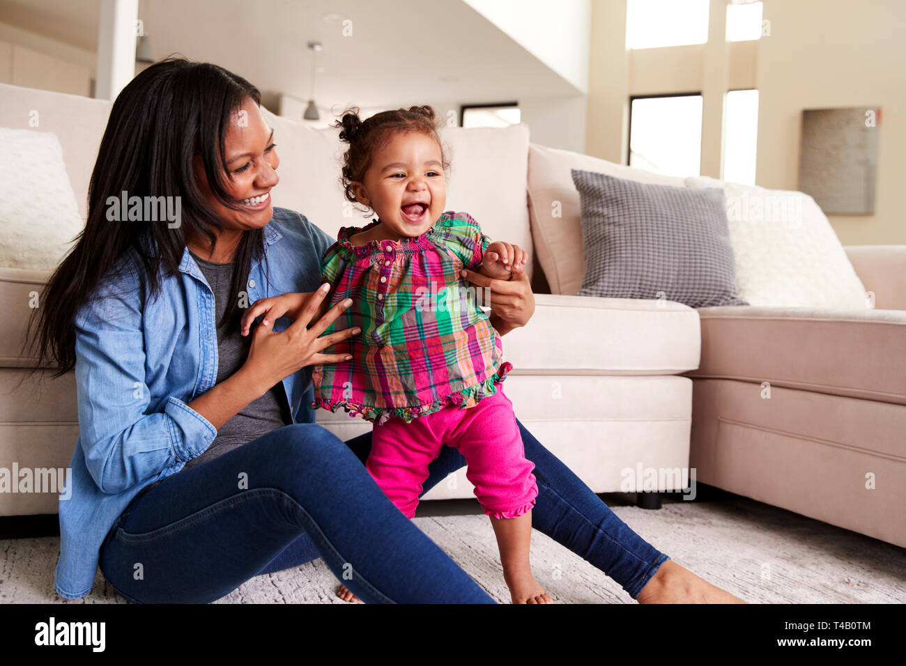 Mutter spielt mit Baby Tochter sitzen auf dem Boden der Lounge zu Hause Stockfoto