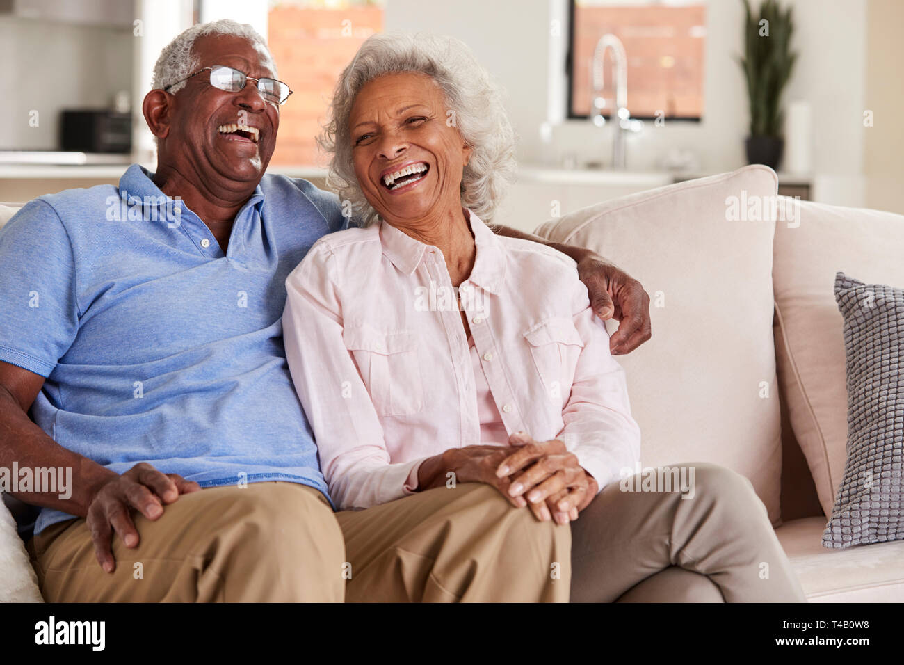 Liebevolle Senior Paar sitzt auf einem Sofa zu Hause und Lachen zusammen Stockfoto