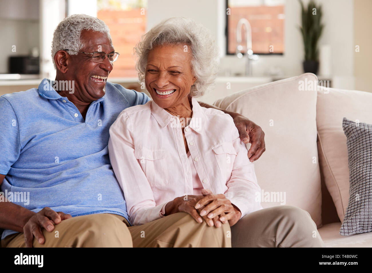 Liebevolle Senior Paar sitzt auf einem Sofa zu Hause und Lachen zusammen Stockfoto
