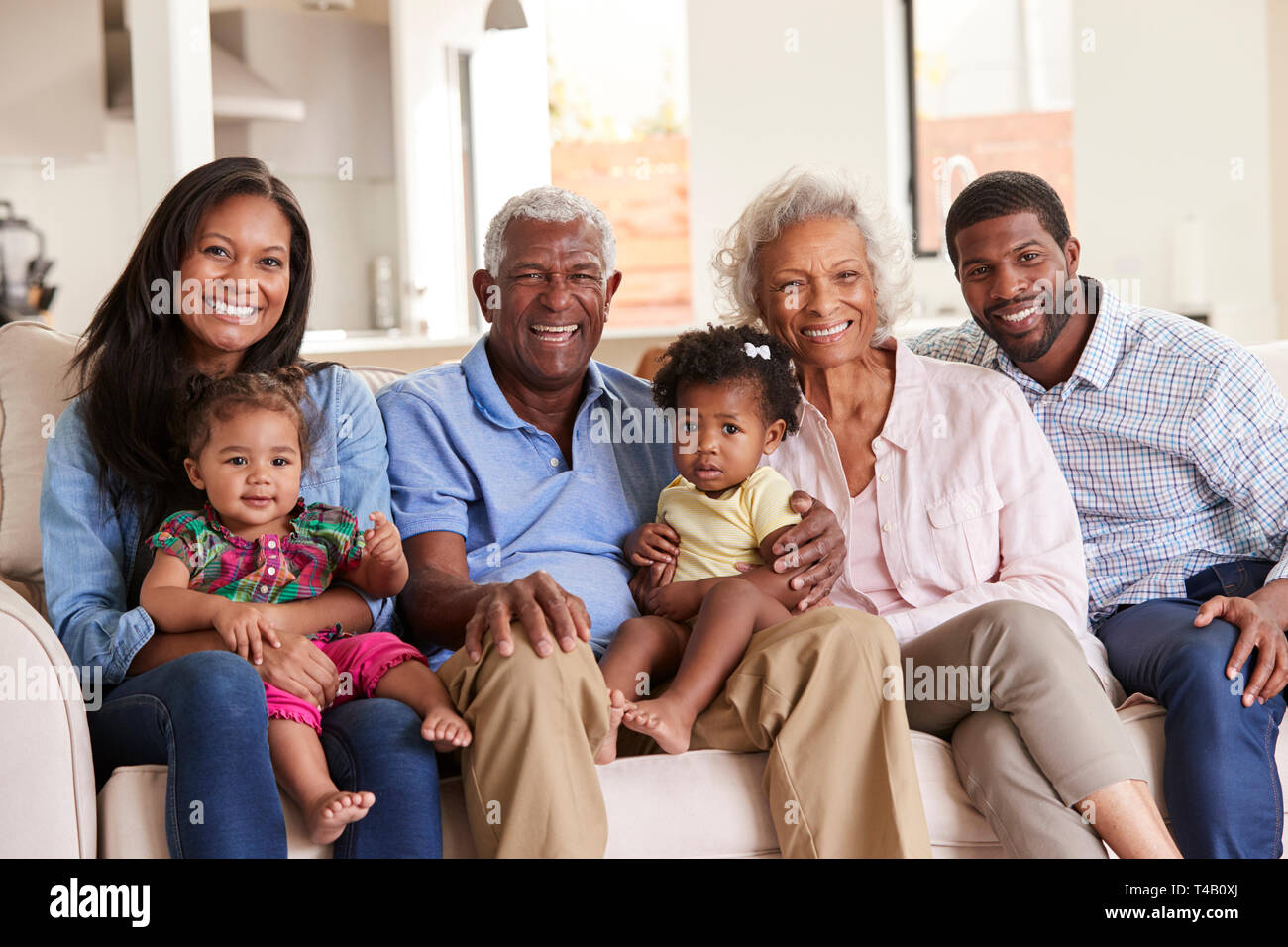 Portrait von Multi-Generation Familie sitzt auf dem Sofa zu Hause mit Baby Enkelinnen Stockfoto