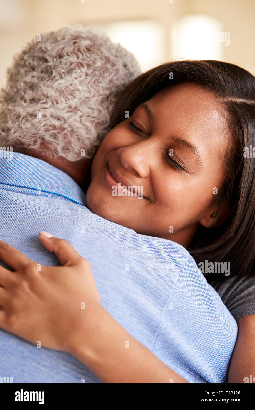 Blick über die Schulter des älteren Vater umarmt von erwachsenen Tochter zu Hause Stockfoto