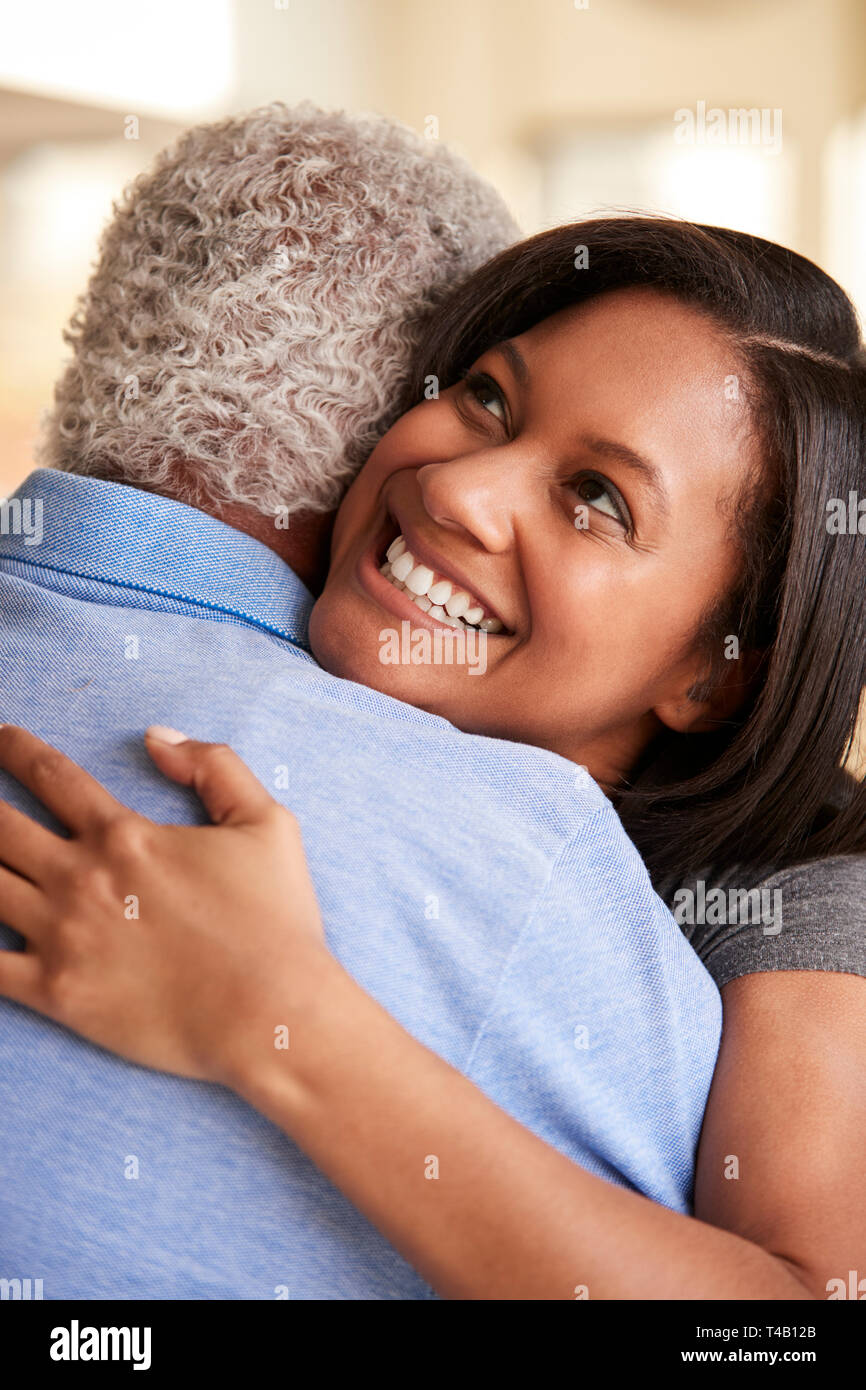 Blick über die Schulter des älteren Vater umarmt von erwachsenen Tochter zu Hause Stockfoto