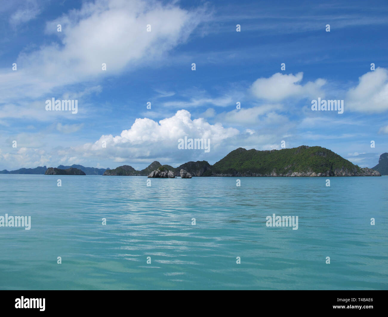 Blauer Himmel mit Wolken und das türkisfarbene Meer verschmelzen am Horizont. Man kann sehen, wunderschöne grüne Inseln im Ozean. Reisen Postkarte. Stockfoto