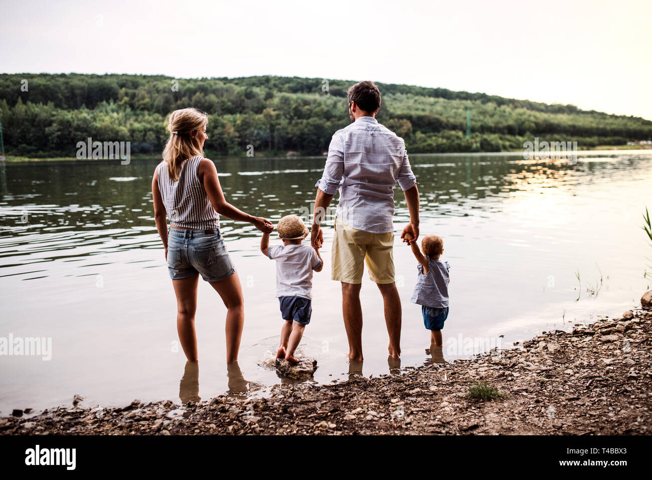 Eine Ansicht der Rückseite des Familie mit zwei Kleinkindern Kinder draußen am Fluss im Sommer. Stockfoto