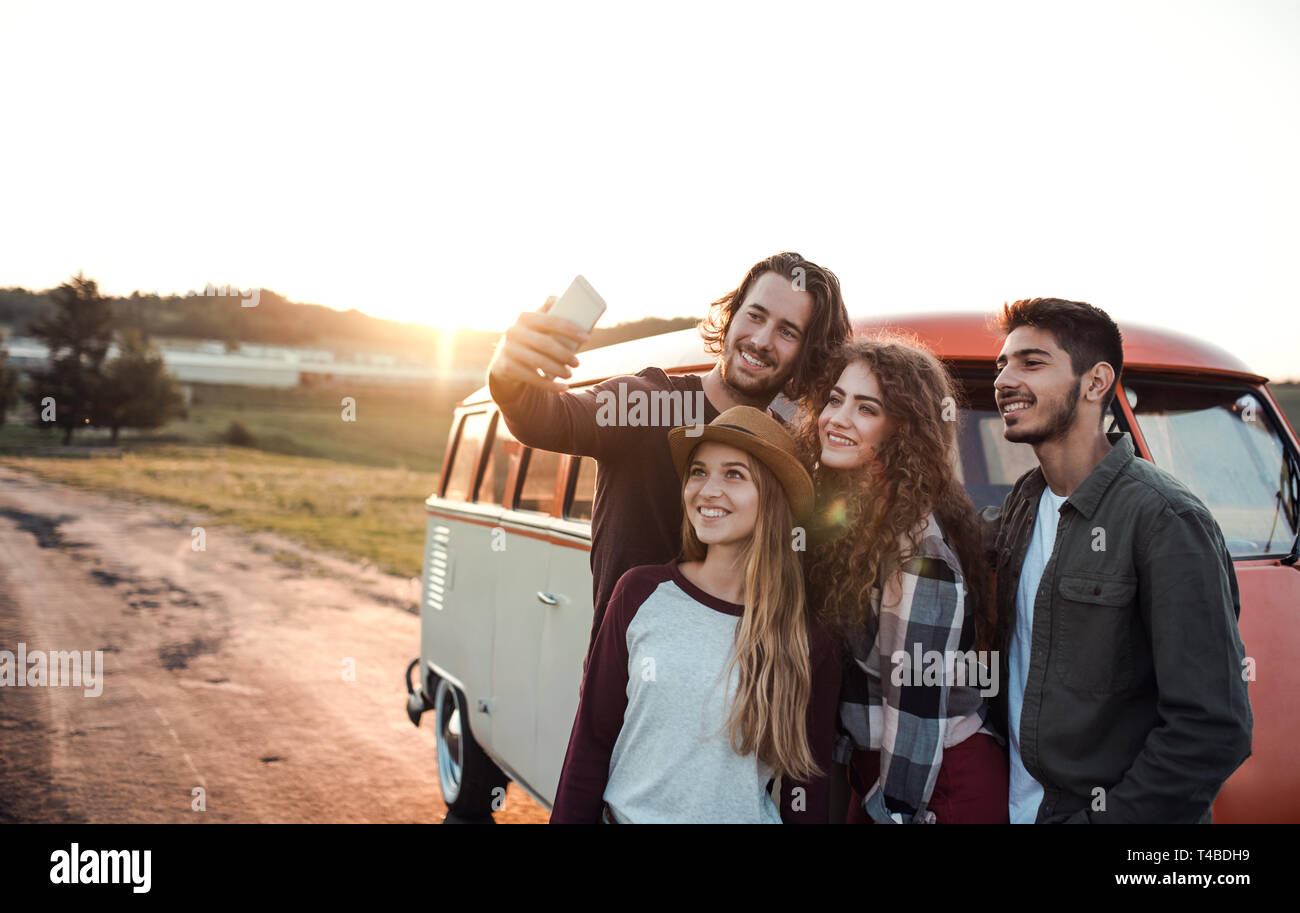 Eine Gruppe junger Freunde auf einem Roadtrip durch Landschaft, wobei selfie. Stockfoto