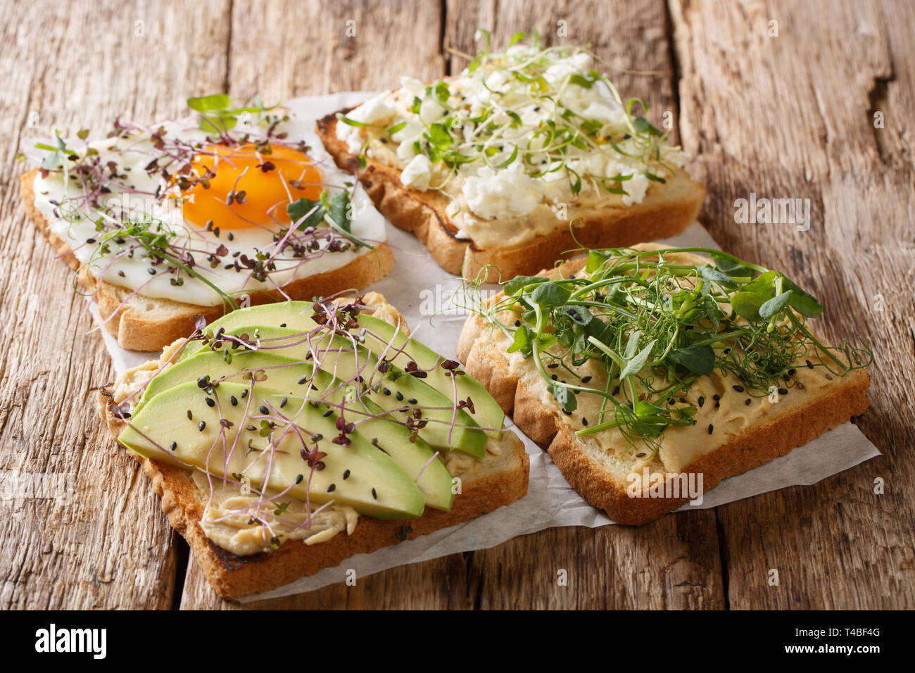 Sandwiches mit Hummus, Avocado, Fetakäse, microgreen und ei Nahaufnahme auf dem Tisch. Horizontale Stockfoto