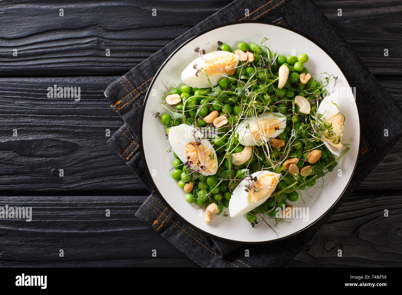 Grüne Feder Salat aus Erbsen, micro Grüns, Nüsse und Eier close-up auf einem Teller auf den Tisch. horizontal oben Ansicht von oben Stockfoto