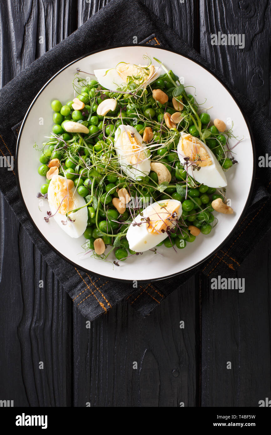 Grüne Feder Salat aus Erbsen, micro Grüns, Nüsse und Eier close-up auf einem Teller auf den Tisch. Vertikal oben Ansicht von oben Stockfoto