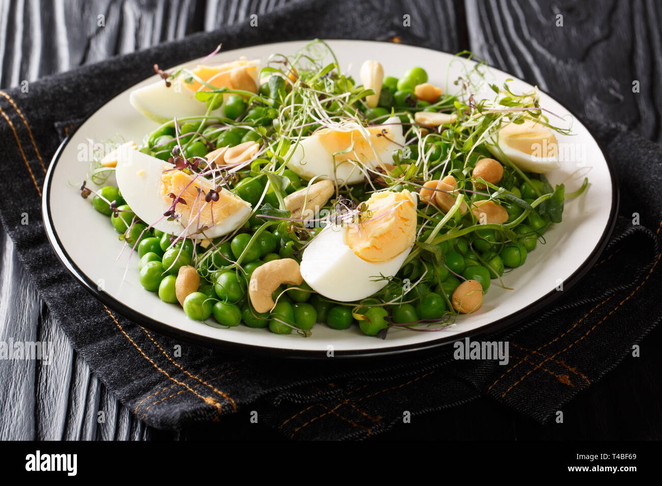 Gesunden Salat mit frischen Erbsen, microgreen, Nüsse und Eier close-up auf einem Teller auf den Tisch. Horizontale Stockfoto