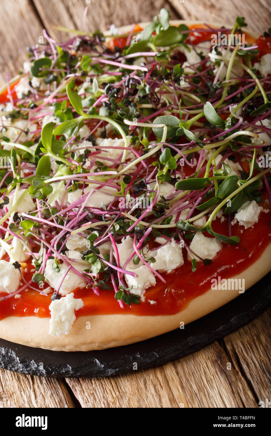 Leckere Pizza mit Feta und Mix microgreen Close-up auf dem Tisch. Vertikale Stockfoto