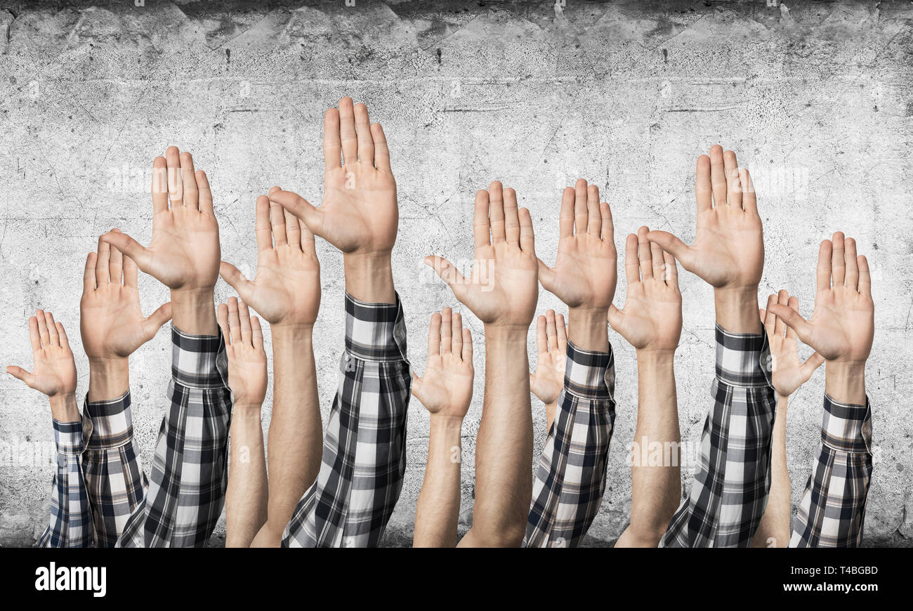 Zeile des Menschen Hände sichtbar Abstimmung Geste. Die Teilnahme und die Vereinbarung Gruppe von Zeichen. Menschliche Hände gestikulierend auf den Hintergrund der graue Wand. Viele Arme heben Stockfoto