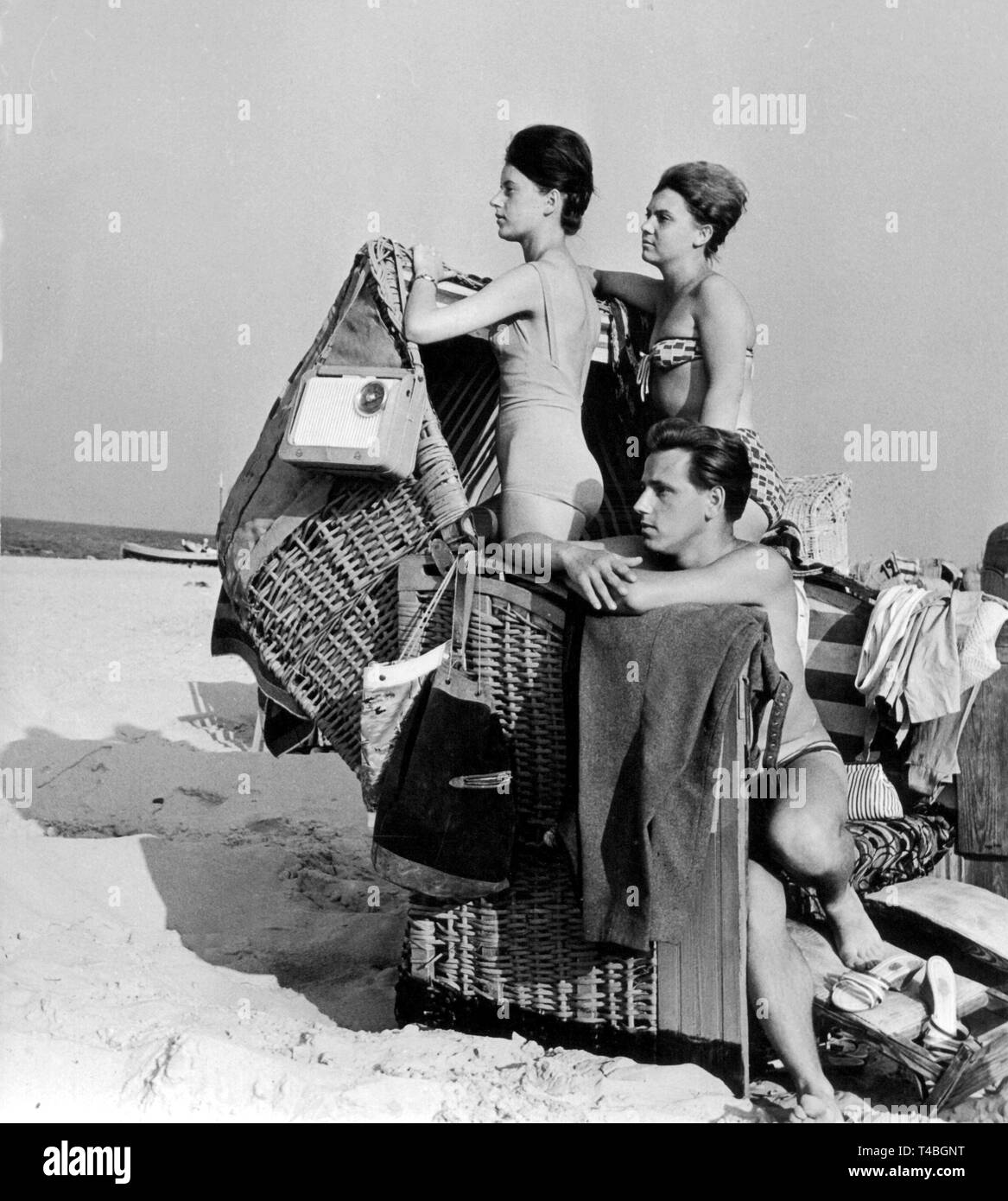 Drei Urlauber beobachten Sie das geschäftige Treiben von ihren Stühlen an der Ostseeküste, 14. Juni 1961. | Verwendung weltweit Stockfoto
