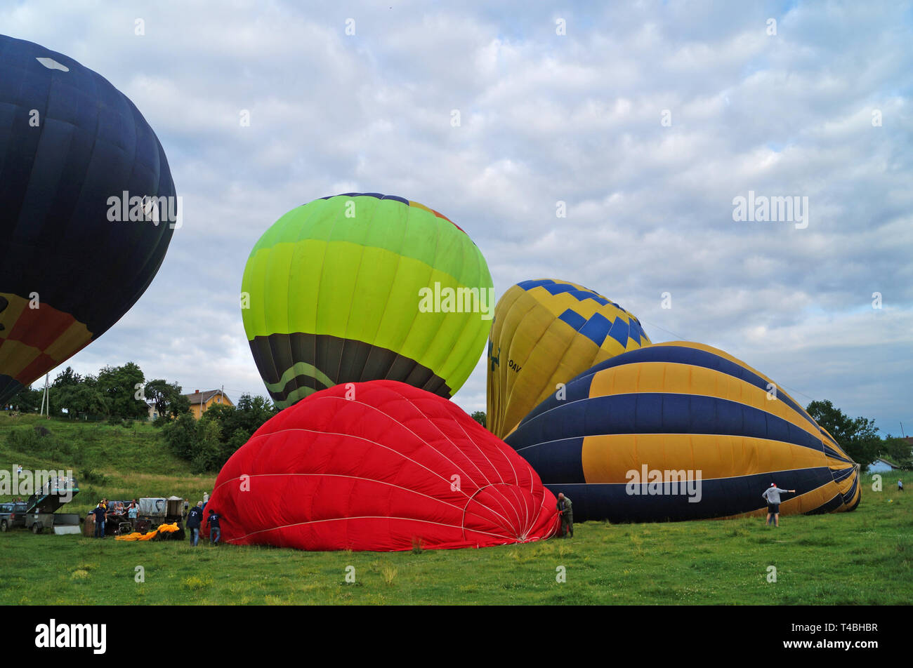 Luftballons in Rot, Blau, Gelb, Grün und Orange aufgeblasen vor dem Aufstieg in den Himmel auf einem Green Glade Stockfoto