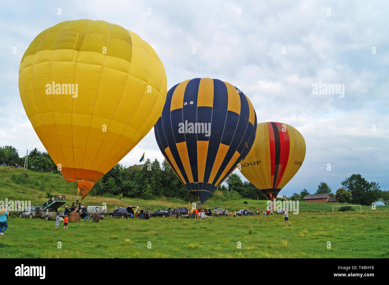 Luftballons Gelb, Blau, Weiß werden aufgeblasen vor dem Fliegen auf einem Green Glade an einem Sommertag. Stockfoto