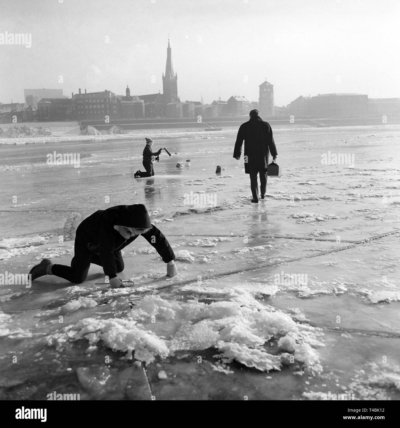 Eine eisdecke von 80 Kilometer Länge hat am Niederrhein auf Grund der Witterungsbedingungen entwickelt. Das Bild zeigt einen Mann, der für einen Spaziergang über den zugefrorenen Rhein am 22. Januar 1963 geht, im Hintergrund der Stadt Düsseldorf. | Verwendung weltweit Stockfoto