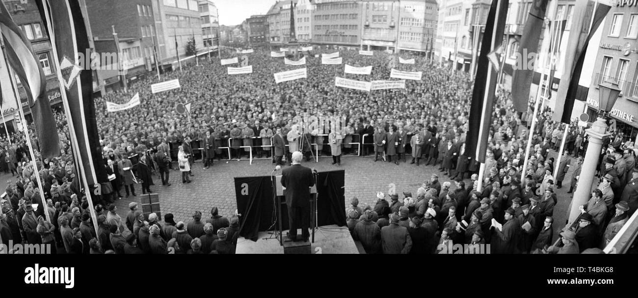 Am 08. Dezember 1963 rund 22.000 zurückkommenden Soldaten mit einem stillen Protest März und einer Kundgebung in Bonn für eine bessere Entschädigung für ehemalige Kriegsgefangene des Zweiten Weltkrieges demonstrieren. Das Bild zeigt die Kundgebung auf dem Marktplatz von Bonn, wo der SPD-Abgeordnete Helmut Bazille gibt eine Rede vor dem Rednerpult. | Verwendung weltweit Stockfoto