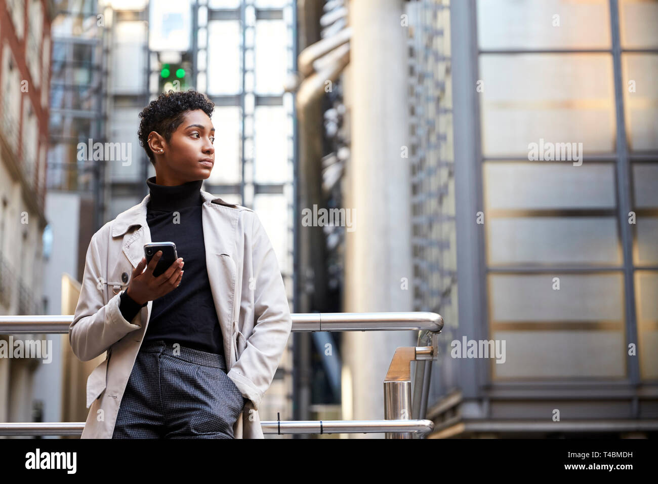 Modische junge schwarze Frau, die in der Stadt halten, Smartphone, niedrigen Winkel Stockfoto