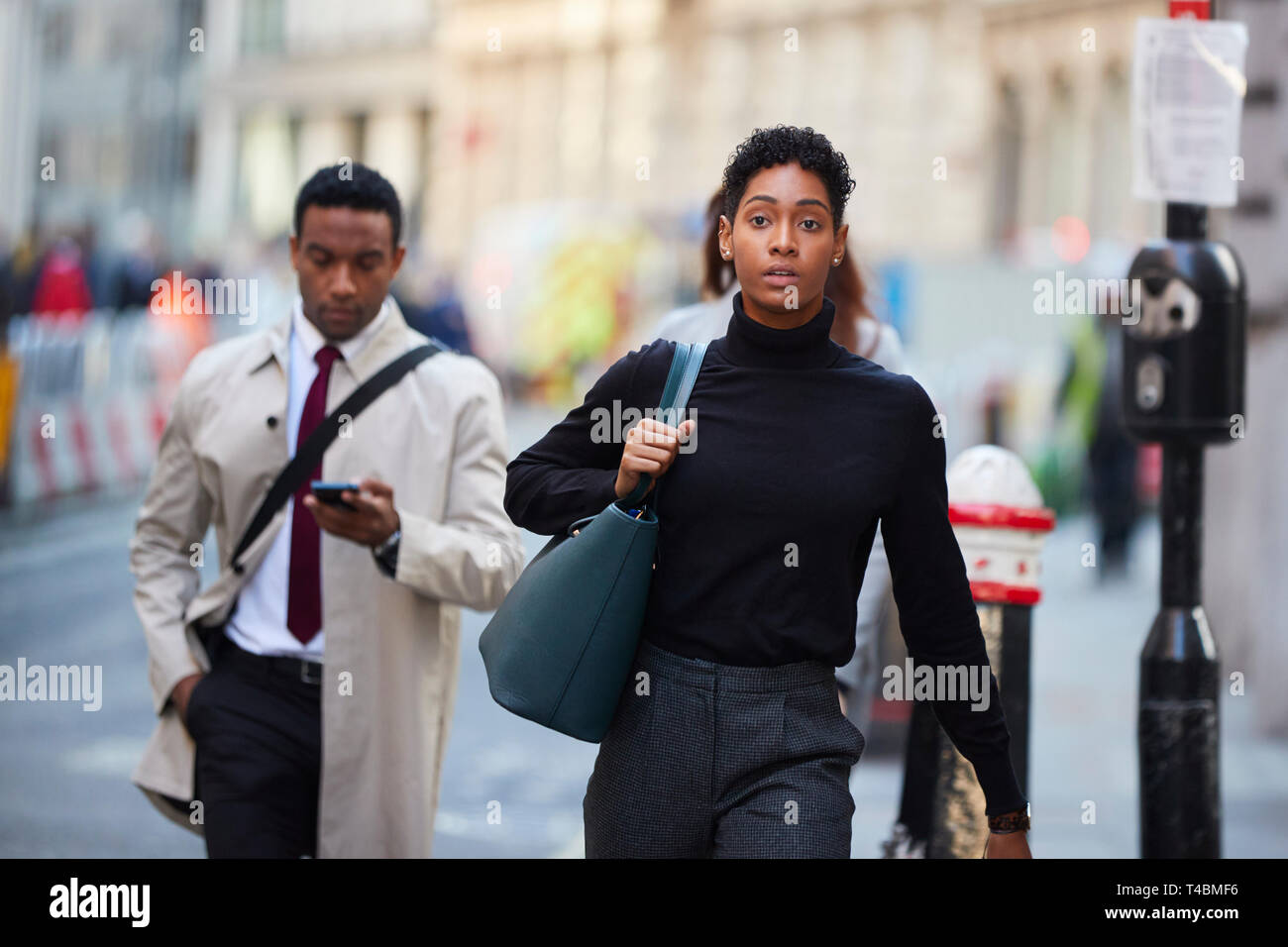 Junge schwarze Frau zu Fuß in einer Londoner Straße, Handtasche, Vorderansicht Stockfoto